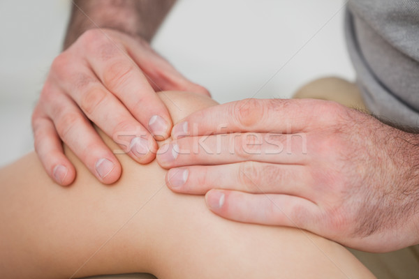 Stock photo: Close-up of hands making a massage on a knee in a room