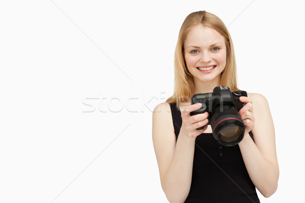 Woman holding a SLR camera while smiling against white background Stock photo © wavebreak_media