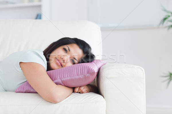 Stock photo: Woman relaxing on a sofa while holding a pillow in a living room