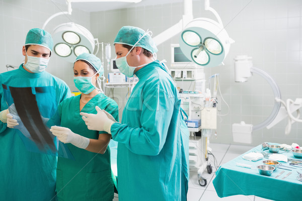 Stock photo: Medical team talking about a X-ray in an operating theatre