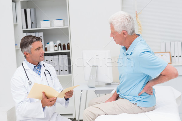Stock photo: Doctor discussing reports with patient suffering from backache