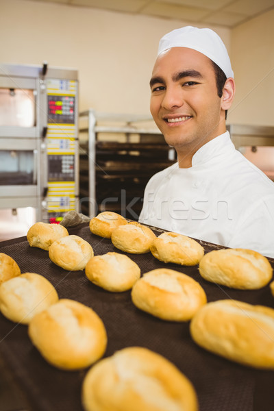 Baker smiling at camera holding tray of rolls Stock photo © wavebreak_media