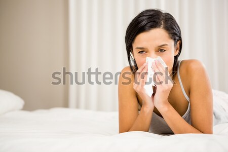 Stock photo: Sick brunette lying on the couch and blowing her nose