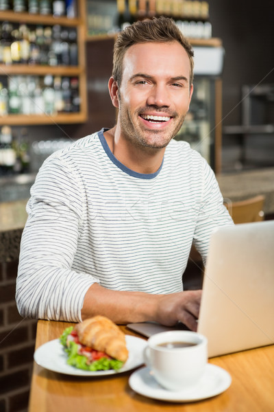 Hombre guapo usando la computadora portátil croissant pub ordenador hombre Foto stock © wavebreak_media