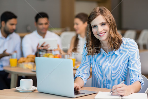 Smiling businesswoman working on laptop while having coffee in office cafeteria Stock photo © wavebreak_media