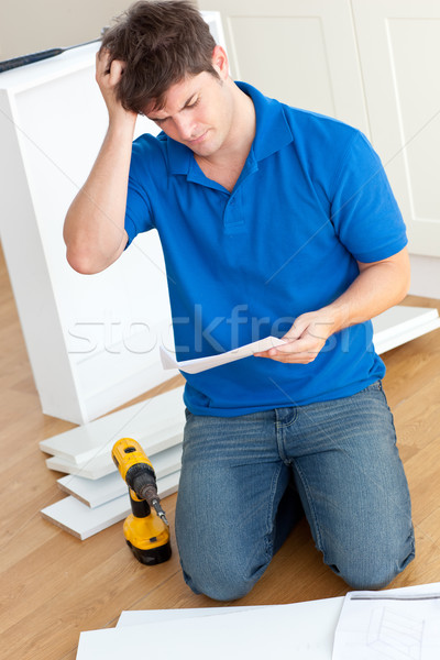 Incomprehensive young man reading the instructions to assemble furniture in the kitchen Stock photo © wavebreak_media