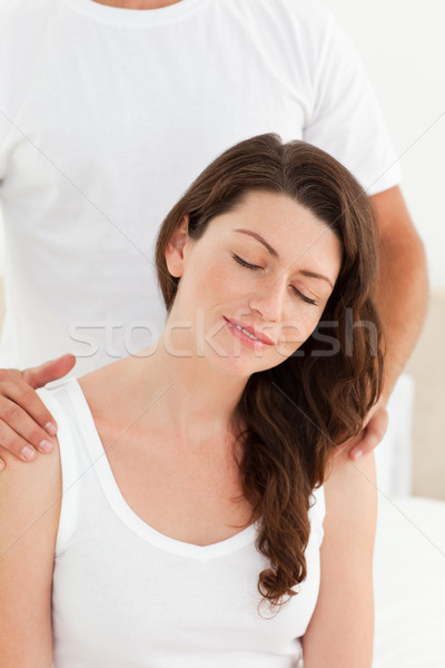 Stock photo: Attentive man massaging his girlfriend's back sitting on their bed at home