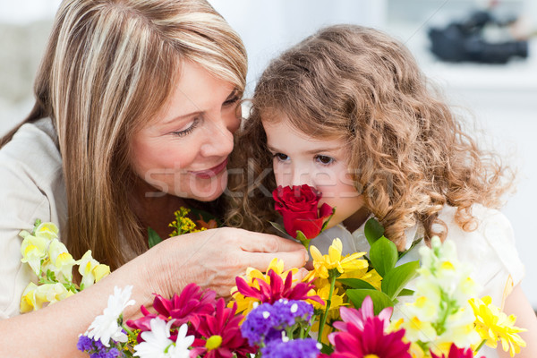 Stock photo: Little girl smelling flowers while her grandmother is smilling