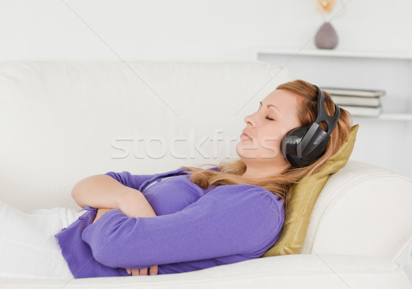 Good looking red-haired woman listening to music while taking a rest lying on a sofa in the living r Stock photo © wavebreak_media