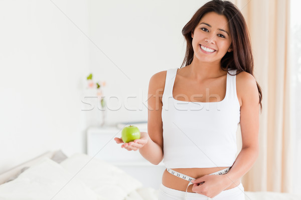 gorgeous woman measuring her waist while holding an apple in bedroom Stock photo © wavebreak_media