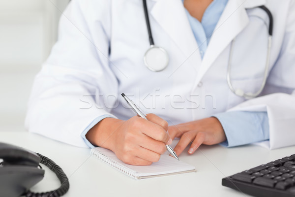 Female doctor with a stethoscope writing on a scratchpad in her office Stock photo © wavebreak_media