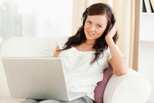 Young woman listening to music looking into camera in the livingroom Stock photo © wavebreak_media