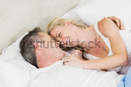 Portrait of a couple under a duvet with a knowing smile in a bed Stock photo © wavebreak_media
