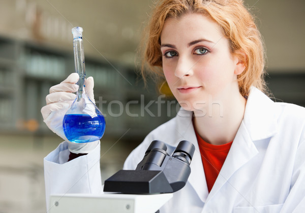Scientist posing with a microscope and a flask in a laboratory Stock photo © wavebreak_media