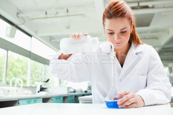 Red-haired focused scientist pouring liquid in a flask in a laboratory Stock photo © wavebreak_media