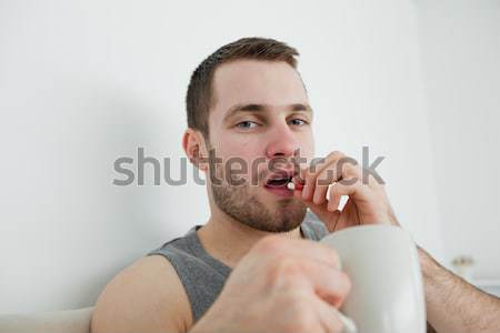 Stock photo: Sick man sneezing in his bedroom