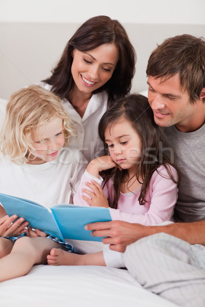 Stock photo: Portrait of a family reading a book in a bedroom
