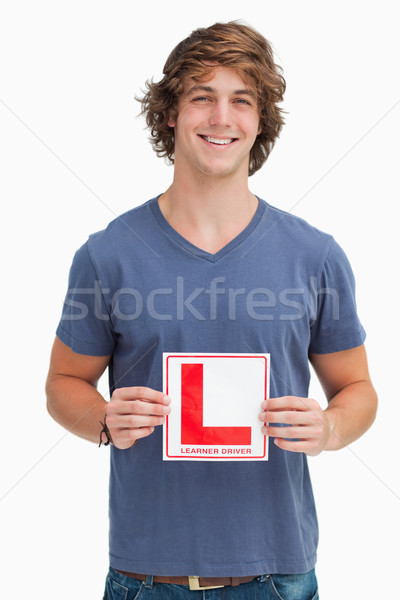Smiling young man holding a learner driver sign against white background Stock photo © wavebreak_media
