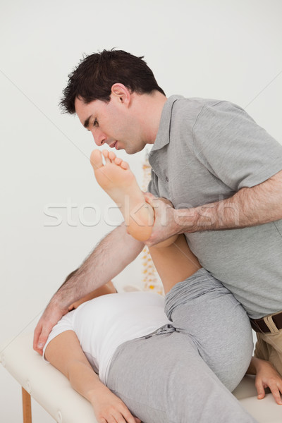 Stock photo: Woman lying while a physio moving her leg in a room