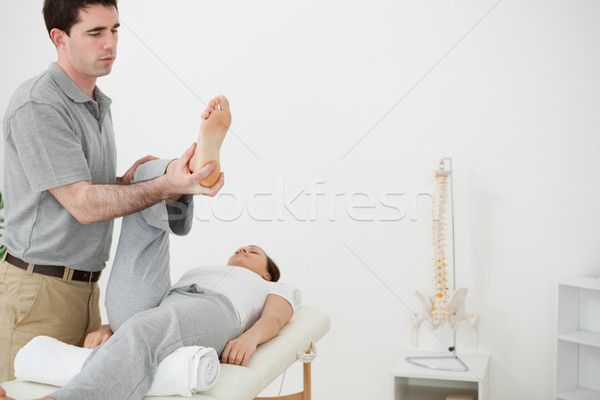 Stock photo: Brunette physiotherapist manipulating the leg of a woman in a room