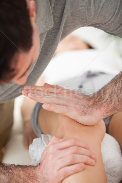 Serious osteopath using the ball of his hand to massage a knee indoors Stock photo © wavebreak_media