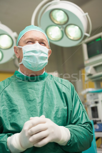 Stock photo: Surgeon joining his hands and smiling in a surgical room