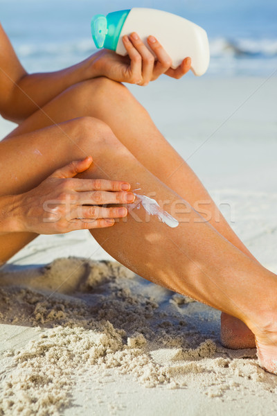 Woman sitting on the beach applying suncream Stock photo © wavebreak_media