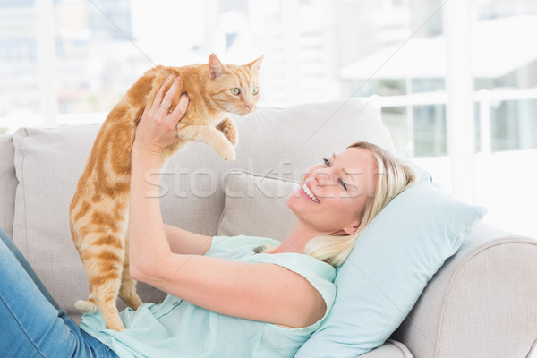 Woman lifting cat on sofa at home Stock photo © wavebreak_media
