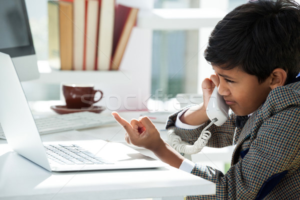 Stock photo: Businessman talking through telephone while pointing on laptop at desk