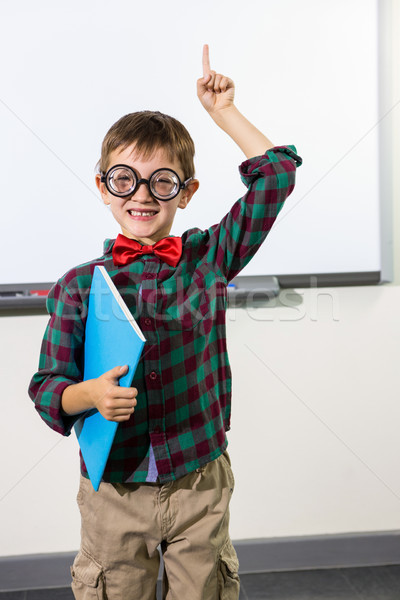 Portrait of cute boy with notebook raising hand in classroom Stock photo © wavebreak_media
