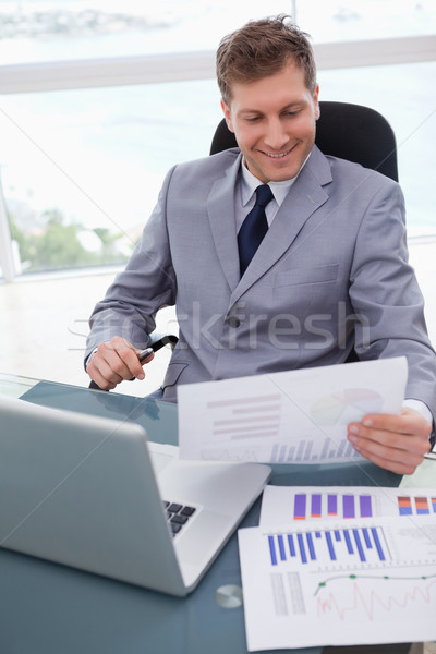 Smiling Businessman At His Desk Looking At Market Research Results