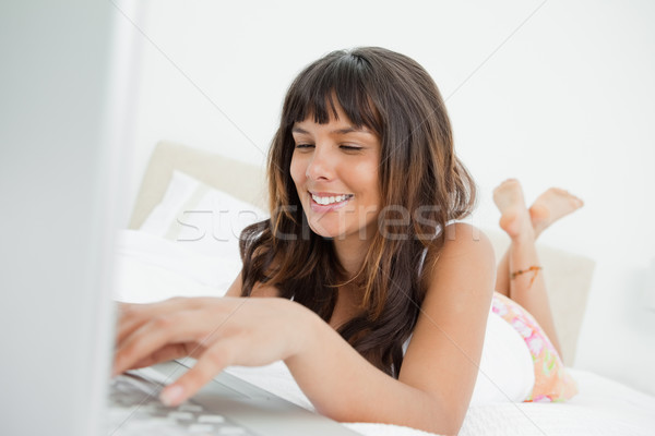 Mujer sonriente portátil cama blanco dormitorio Foto stock © wavebreak_media