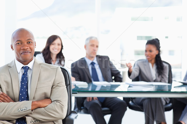 Young executive almost smiling in front of his team which is sitting in the back Stock photo © wavebreak_media