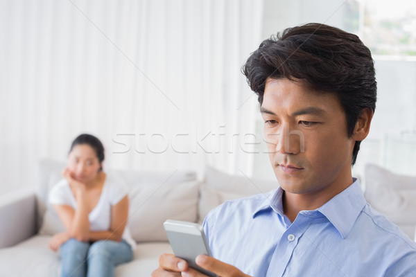 Man sending a text while girlfriend watches from couch Stock photo © wavebreak_media
