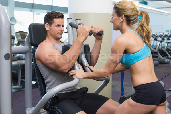 Stock photo: Personal trainer coaching bodybuilder using weight machine