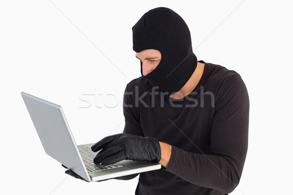 Focused burglar standing holding laptop Stock photo © wavebreak_media