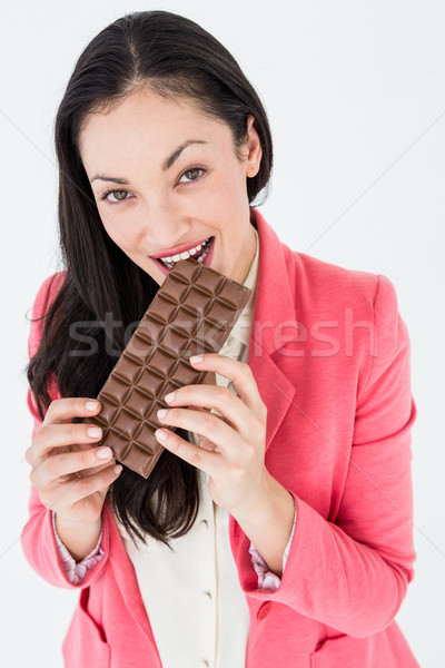 Smiling brunette biting bar of chocolate Stock photo © wavebreak_media