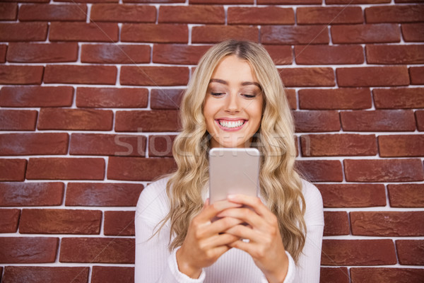 Mooie blonde vrouw glimlachend smartphone Rood baksteen Stockfoto © wavebreak_media