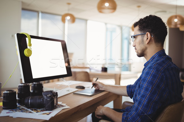 Stock photo: Attentive graphic designer using graphic tablet at desk