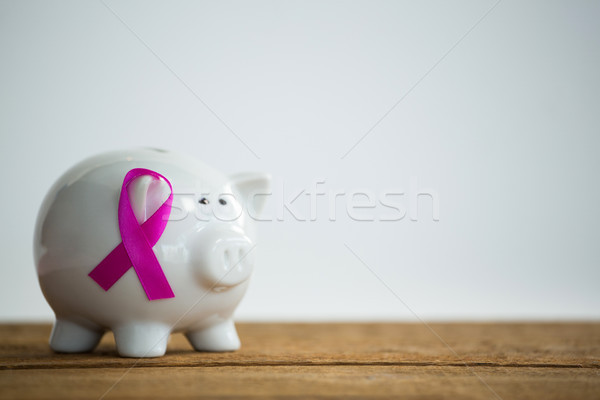 Close-up of pink Breast Cancer Awareness ribbon on piggybank over wooden table Stock photo © wavebreak_media