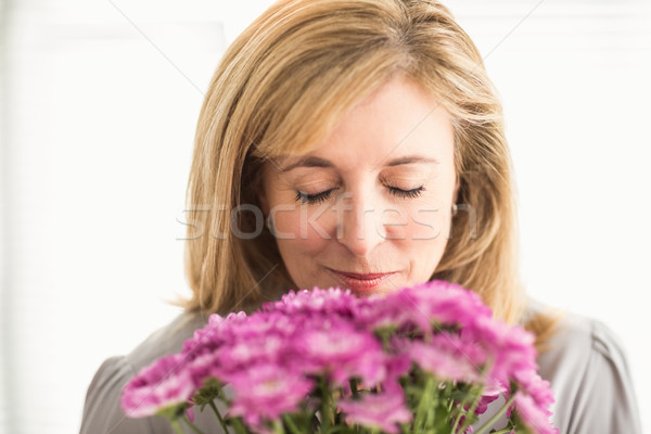 Casual businesswoman smelling at flowers Stock photo © wavebreak_media