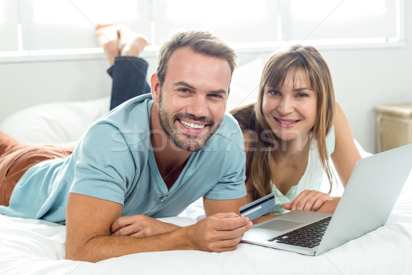 Happy couple online shopping while relaxing on bed Stock photo © wavebreak_media