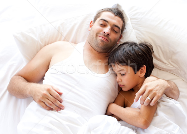 Confident father and his son looking at the camera on the bed Stock photo © wavebreak_media