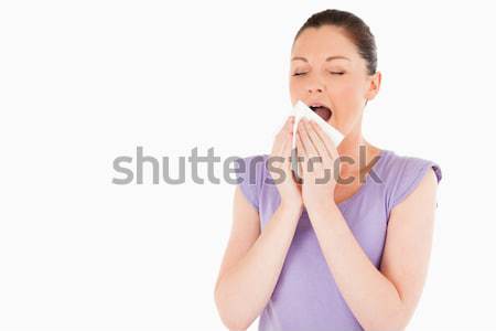 Beautiful woman sneezing while standing against a white background Stock photo © wavebreak_media