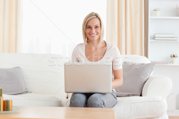 Cute woman using a laptop while sitting on a sofa Stock photo © wavebreak_media