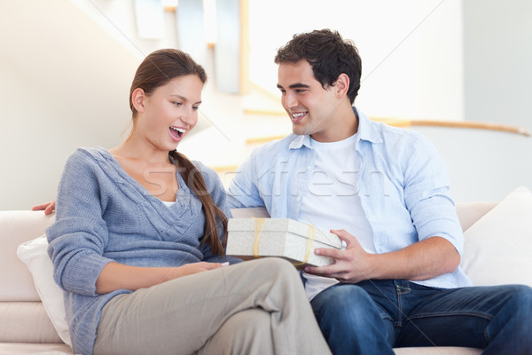 Stock photo: Man offering a gift to his fiance in their living room