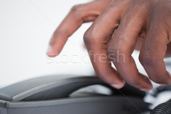 Stock photo: Close up of a masculine hand taking a phone handset against a white background