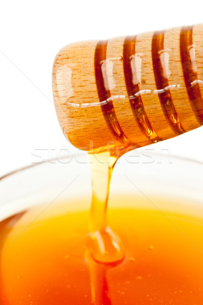 Honey sticky trickle on a dipper dropping in a honey bowl agaisnt a white background Stock photo © wavebreak_media