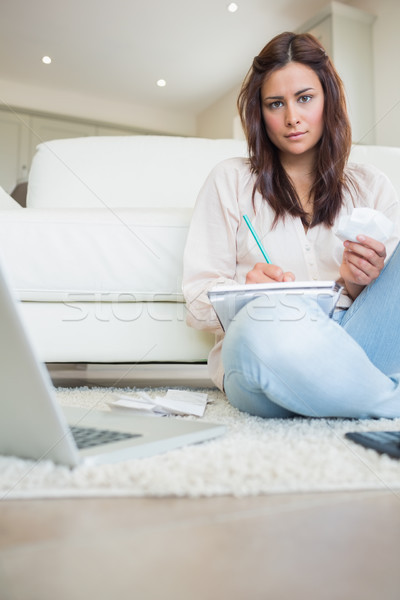 Woman writing on a paper while calculating bills Stock photo © wavebreak_media