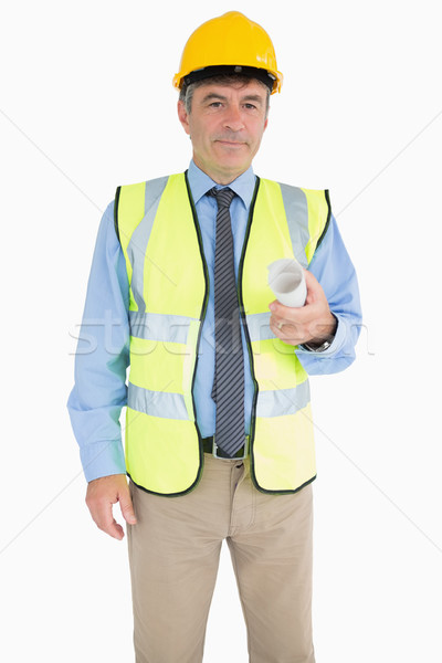 Stock photo: Architect in vest and helmet holding a rolled up plan while smiling